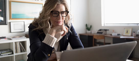 A healthcare professional in an office looks at a laptop.