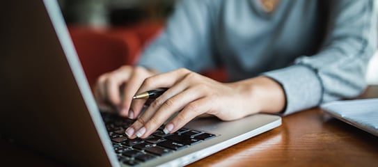 A healthcare professional types on a laptop.