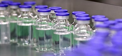 Vials with blue caps filled with a clear liquid in a Johnson & Johnson research lab.